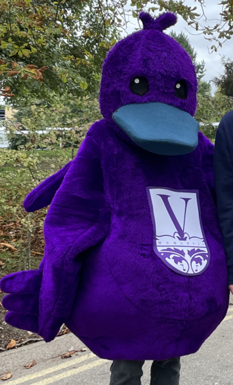 A purple duck mascot with the Vanbrugh College logo on the front