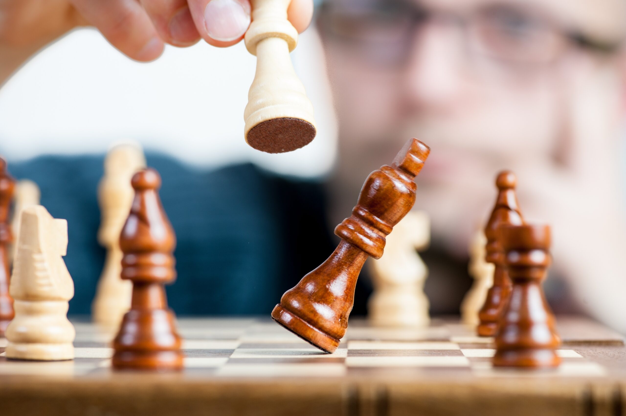 A man places a chess piece as another piece falls over